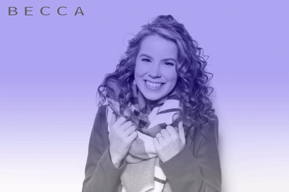 Becca Glam GIF Booth Woman with curly hair poses in a GIF Booth, as her image is captured and converted to black and white with a glam filter applied and purple image overlay