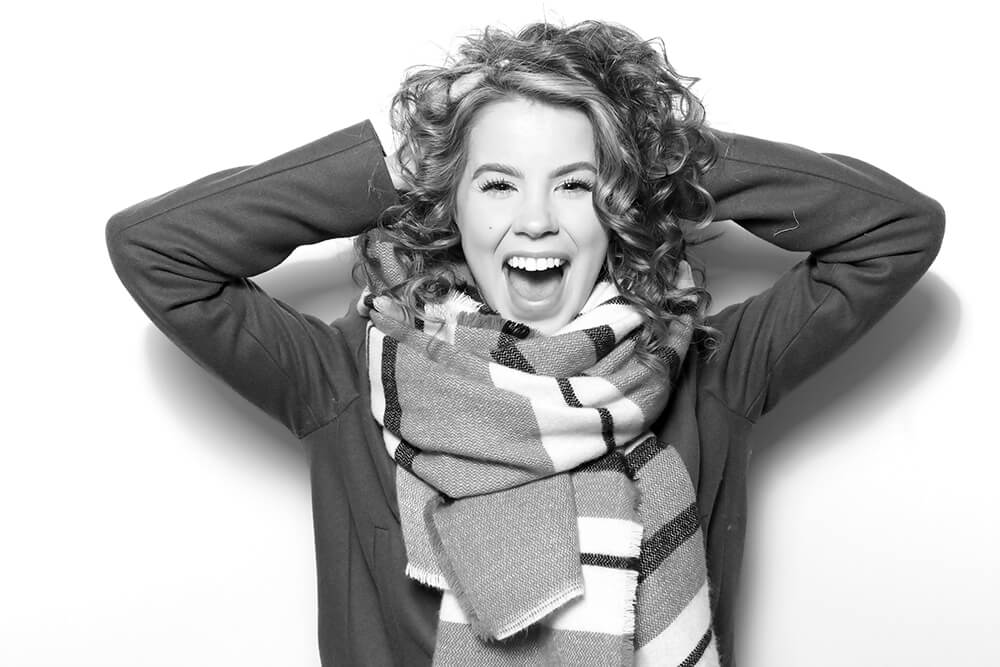 Becca Glam Booth A black and white photo of a woman with curly hair and a skin softening glam filter is applied to the image
