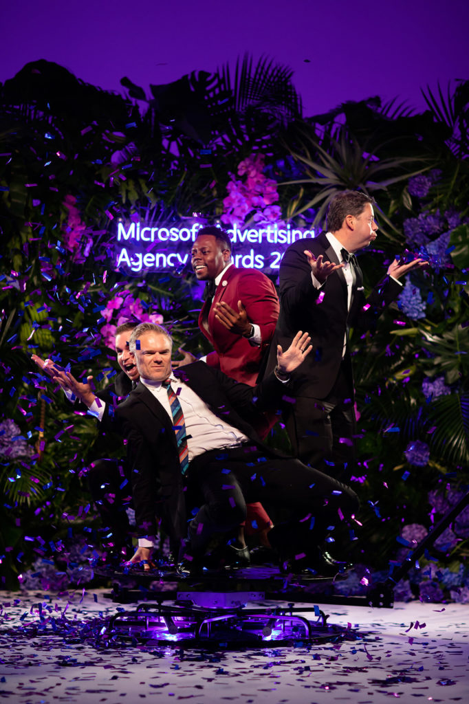 4 men throwing confetti on a 360 photo booth platform